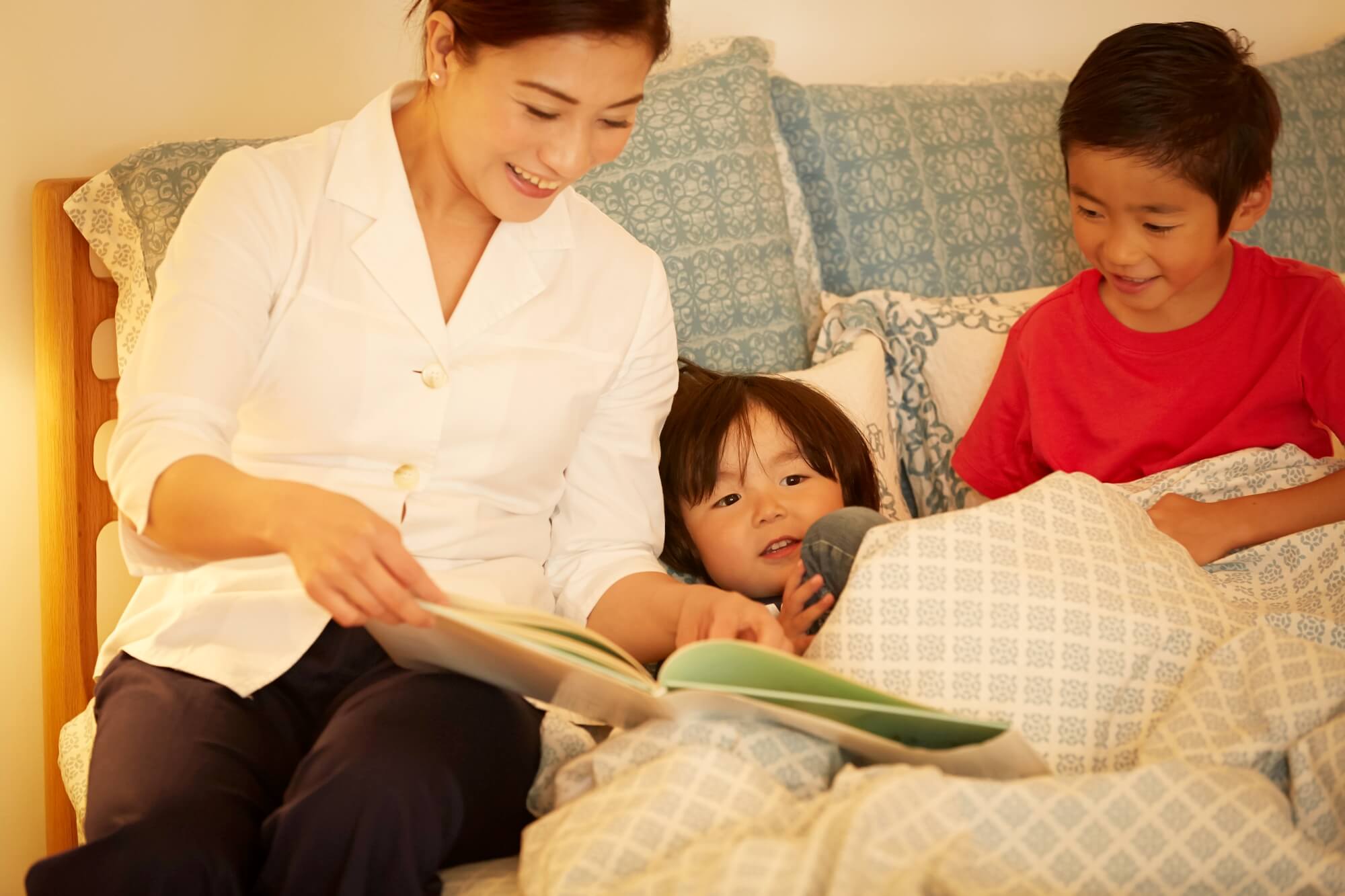 夜にシッターが子供に絵本を読んでいるイメージ